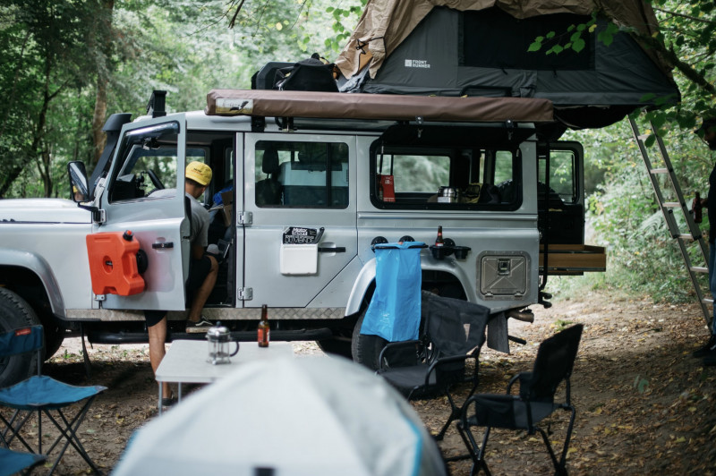 Un 4x4 Land Rover Defender 110 avec sa tente front runner sur un spot de bivouac