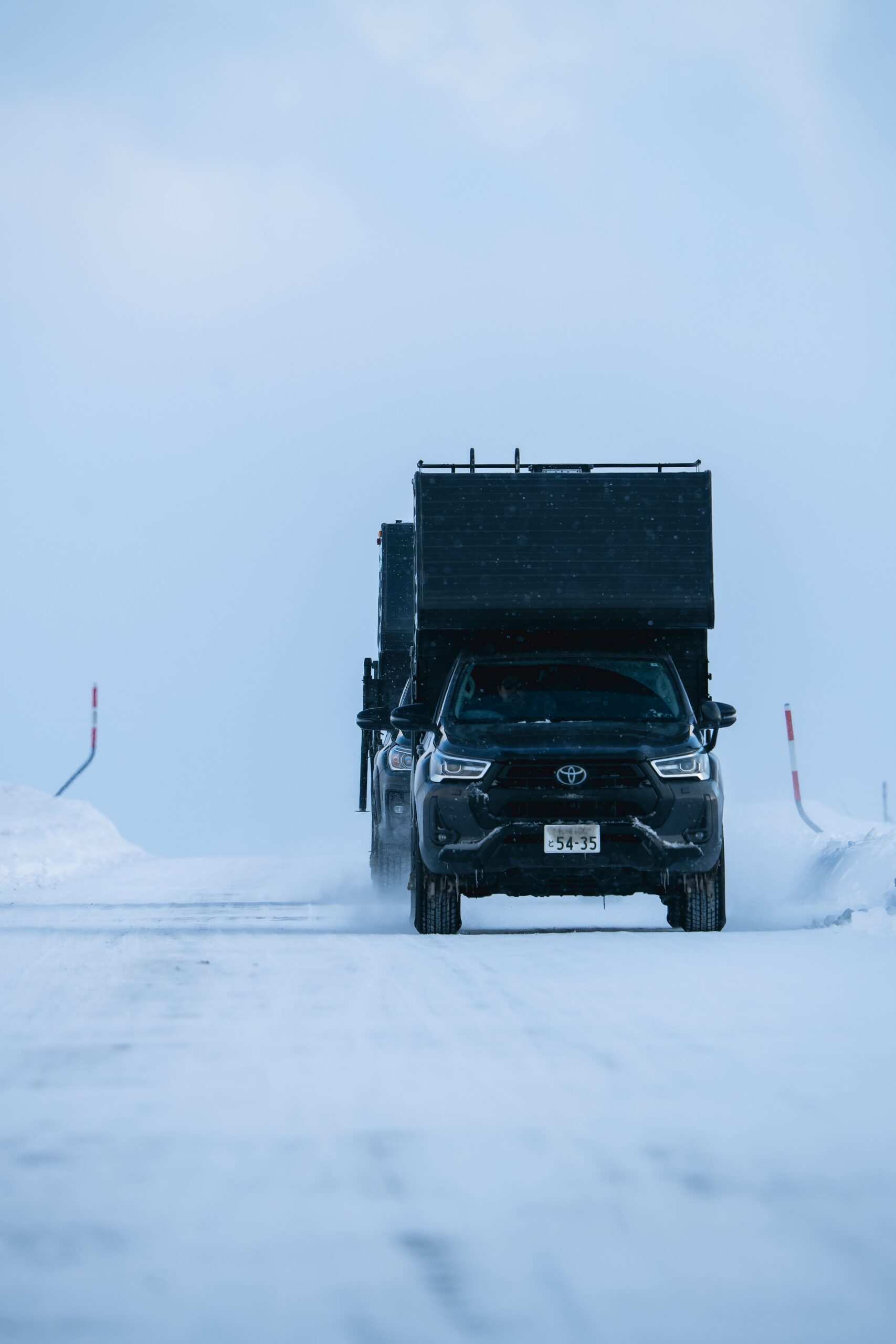 Skieurs de randonnée et 4x4 aménagé au bord d’un fjord enneigé en Islande