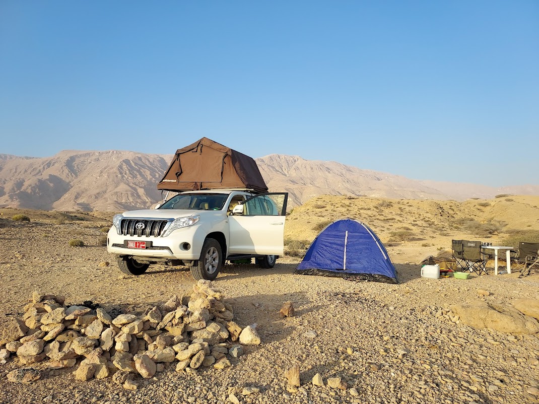 Bivouac en pleine nature à Oman avec un 4x4 aménagé face aux montagnes