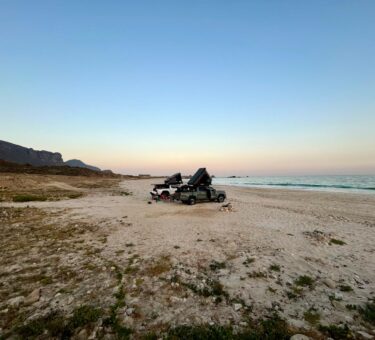 deux véhicules d'aventure garés sur une plage à oman