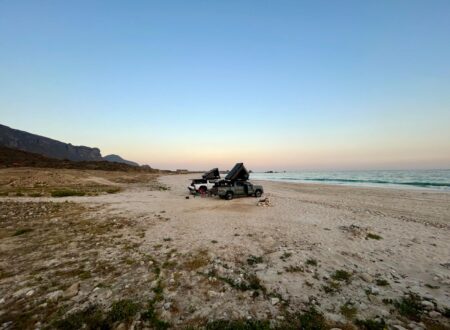 deux véhicules d'aventure garés sur une plage à oman
