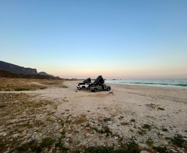 deux véhicules d'aventure garés sur une plage à oman