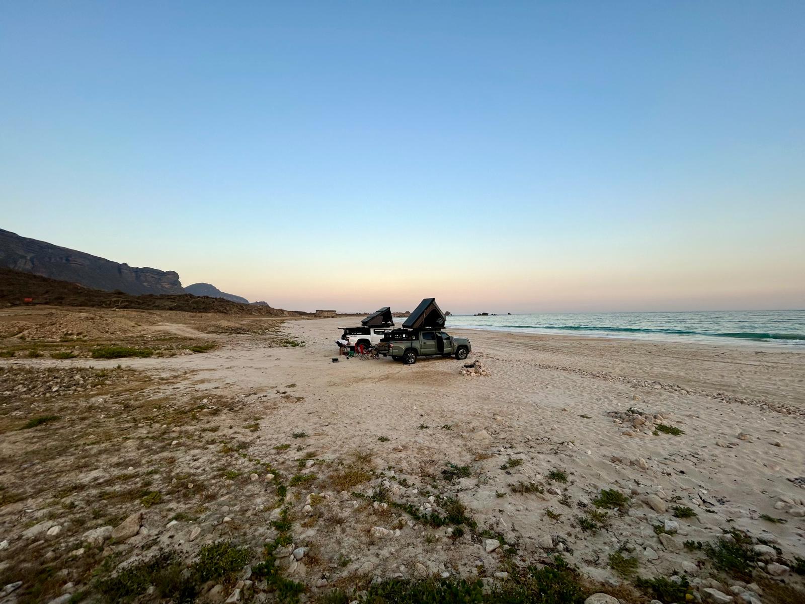 deux véhicules d'aventure garés sur une plage à oman