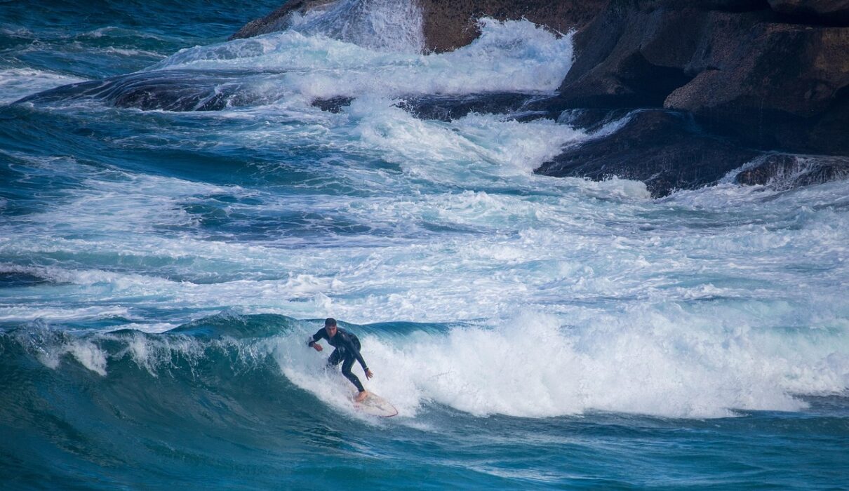 Surfeur en combinaison intégrale sur une vague de la péninsule de Reykjanes en Islande