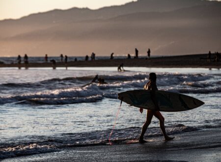 surfer-silhouette-marchant-au-bord-de-la-mer-au-coucher-du-soleil-scaled