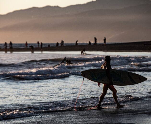 surfer-silhouette-marchant-au-bord-de-la-mer-au-coucher-du-soleil-scaled