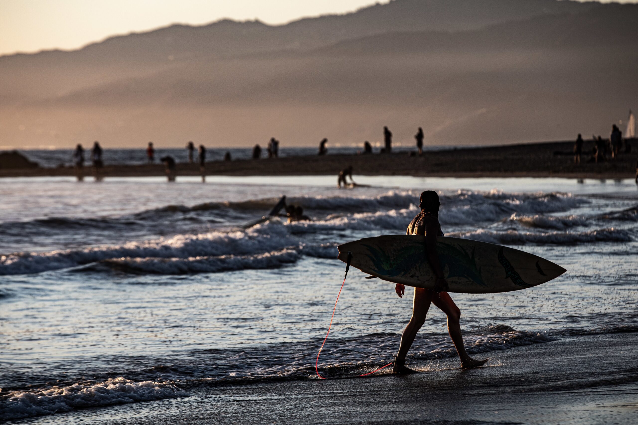surfer-silhouette-marchant-au-bord-de-la-mer-au-coucher-du-soleil-scaled