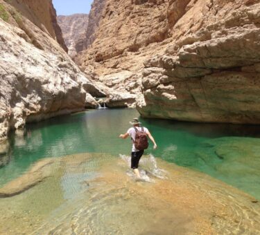 un voygauer se biagnant dans un wadis à Oman durant son road trip en 4X4 aménagé de location