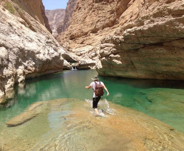 un voygauer se biagnant dans un wadis à Oman durant son road trip en 4X4 aménagé de location