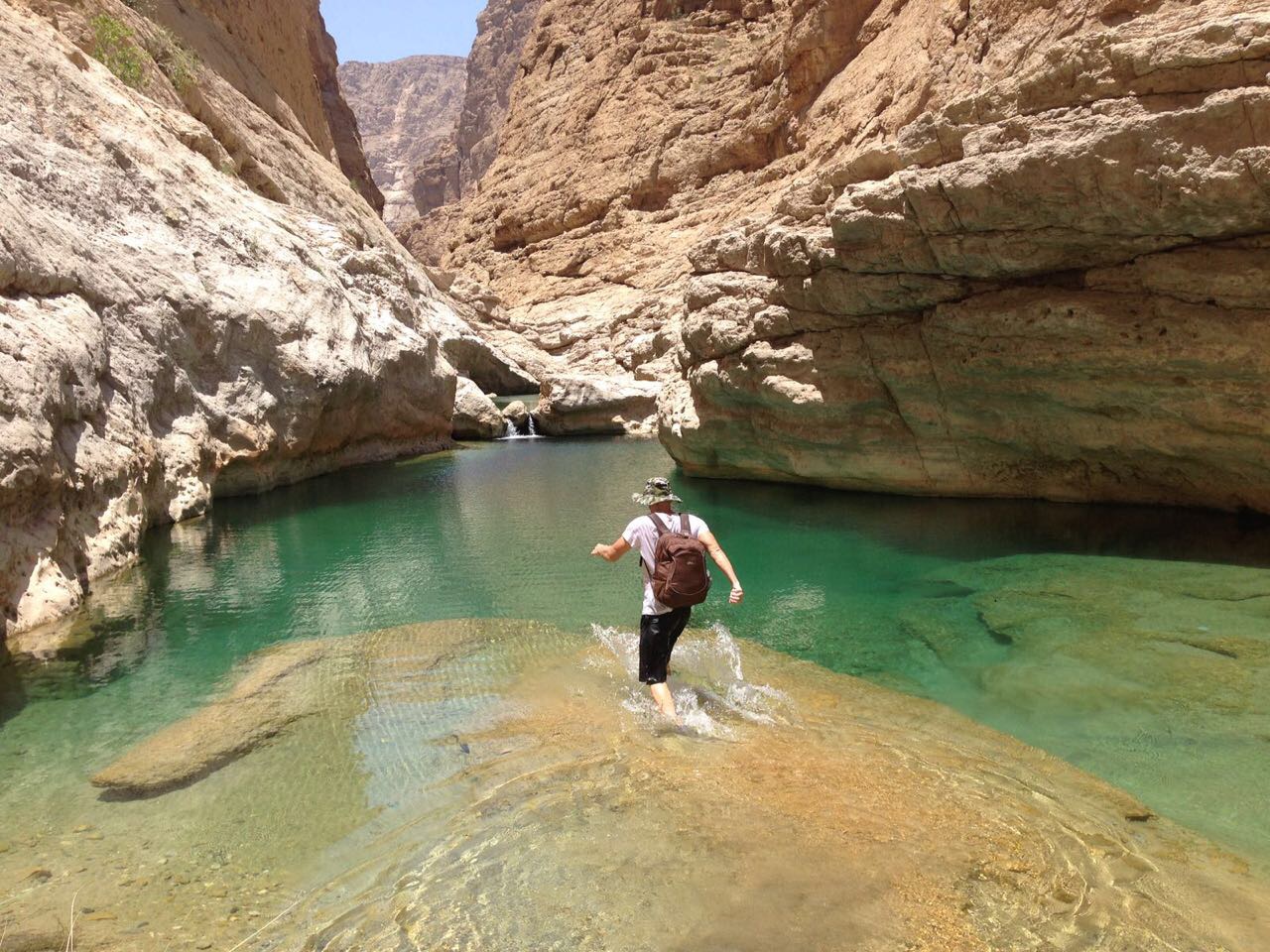un voygauer se biagnant dans un wadis à Oman durant son road trip en 4X4 aménagé de location